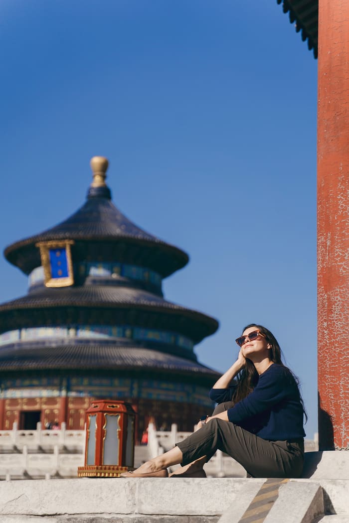 mujer posando para una fotografía con un templo chino de fondo